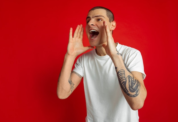 Llamando a ventas. Retrato de hombre joven caucásico en estudio rojo.