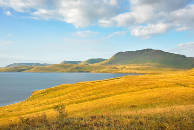 Llanuras cubiertas de hierba verdes colinas en el horizonte bajo un cielo nublado Siberia Rusia