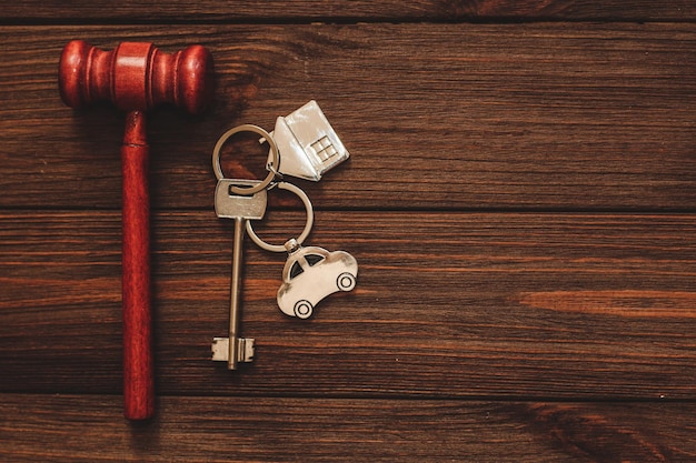 La llave del apartamento con llavero y coche en forma de casa sobre fondo de madera