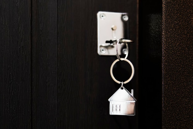 Llave de casa con llavero modelo de casa en el proceso de apertura de la puerta principal del apartamento