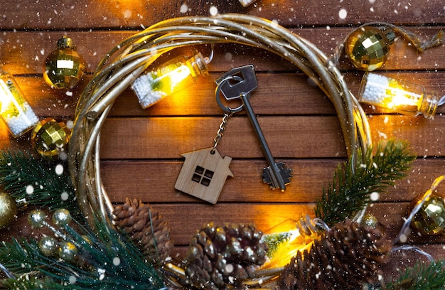 Llave de la casa con un llavero pequeña casa en fondo de madera con diseño de decoración de Navidad