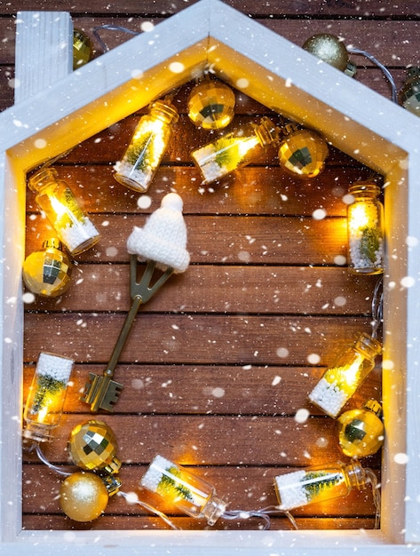 Llave de la casa con un llavero pequeña casa en fondo de madera con diseño de decoración de Navidad