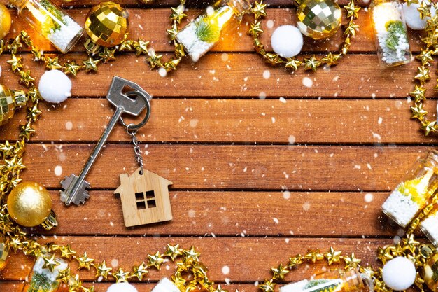 Llave de la casa con un llavero pequeña casa en fondo de madera con diseño de decoración de Navidad