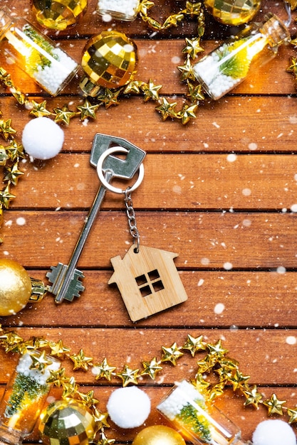 Llave de la casa con un llavero pequeña casa en fondo de madera con diseño de decoración de Navidad