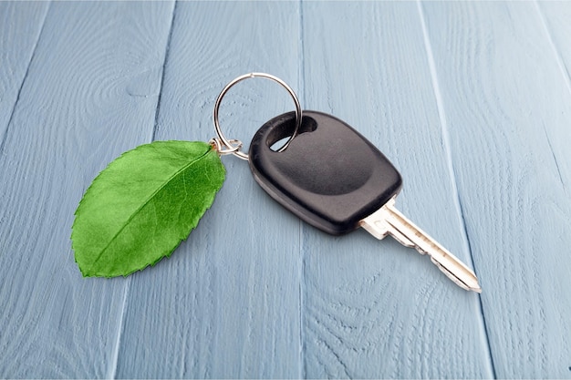 Llave de coche con hoja sobre mesa de madera