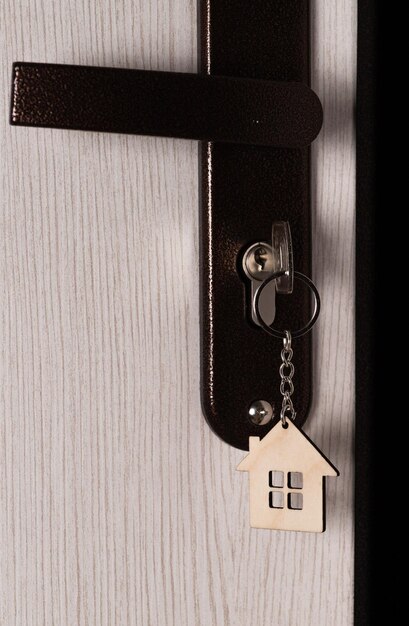 Una llave con un llavero en forma de casa en el ojo de la cerradura de la puerta