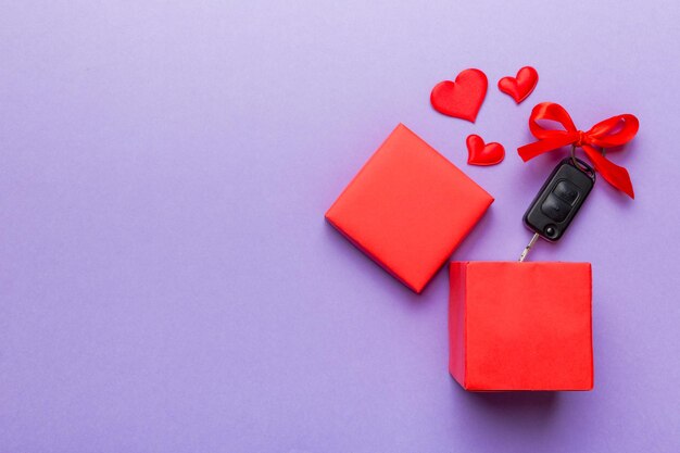 Llave negra del coche en una caja de regalo con una cinta y un corazón rojo sobre fondo de color Composición del día de San Valentín Vista superior