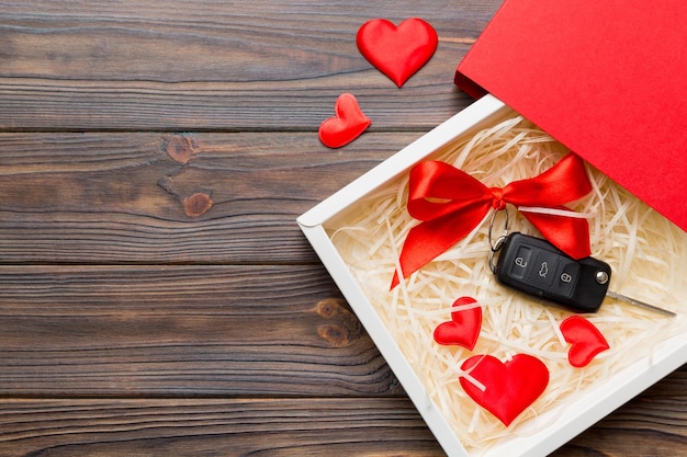 Llave negra del coche en una caja de regalo con una cinta y un corazón rojo sobre fondo de color Composición del día de San Valentín Vista superior