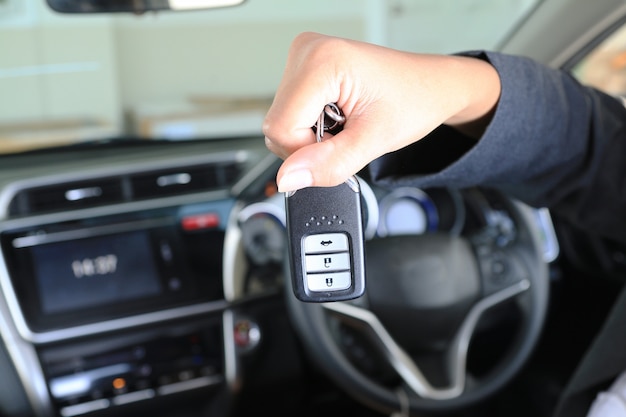 Llave remota de la demostración de la mujer de negocios en coche moderno del vehículo.