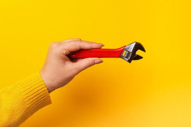 Foto llave roja en mano femenina, maestro con la herramienta