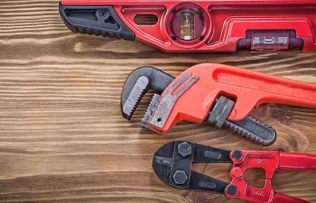 Llave de tubo de nivel de construcción de cortador de pernos en concepto de mantenimiento de tablero de madera vintage