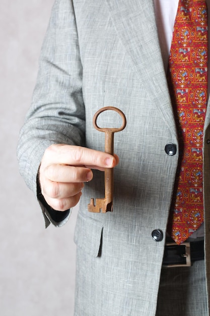 Una llave vintage en la mano de un hombre con un traje clásico.
