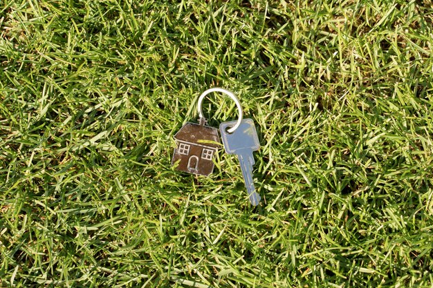 Foto las llaves de la casa con un llavero en forma de casa en el césped verde
