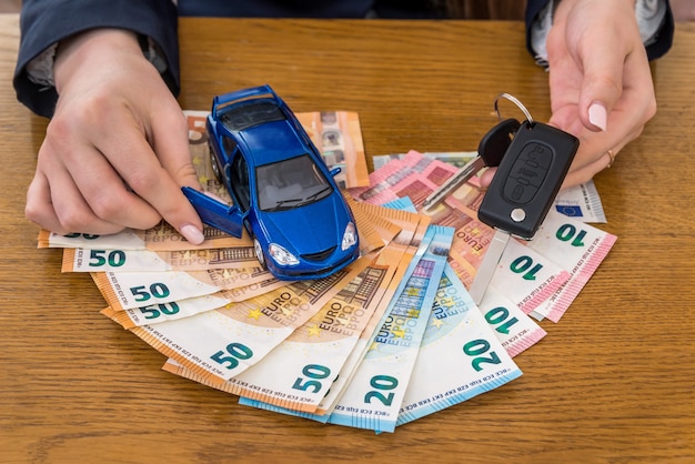 Llaves y coche de juguete en dinero euro, manos femeninas