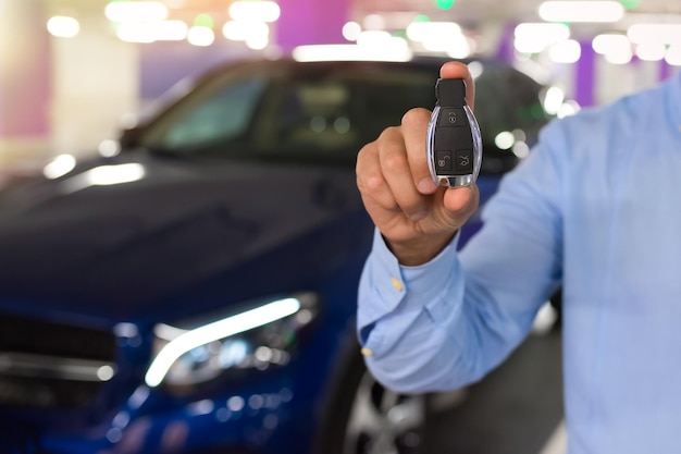 Llaves del coche Mano masculina sosteniendo la llave del coche en un fondo de estacionamiento