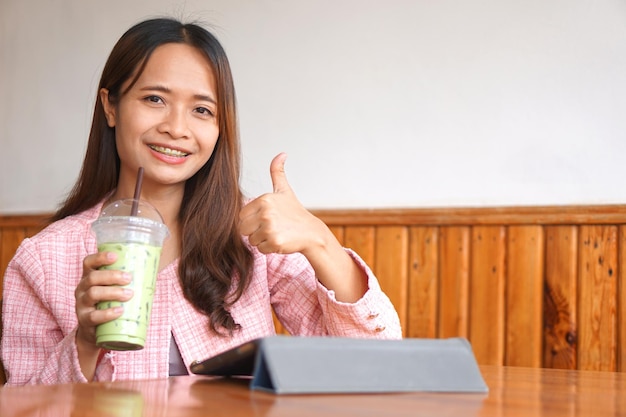 Llaves de mujer asiática ver computadora Beber té verde para refrescarse