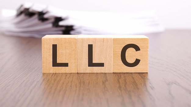 LLC-Buchstaben auf Holzblockwürfeln auf Holztisch Akronym LLC Limited Liability Company