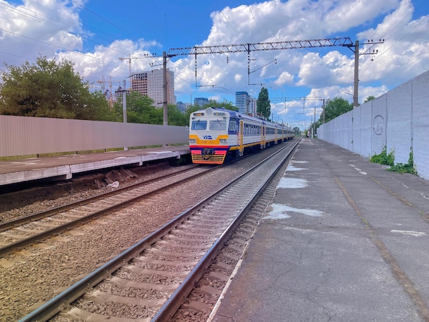 Llegada de un tren eléctrico Un tren urbano moderno llega a la estación Kiev Edificios de trenes circulares en construcción en el fondo