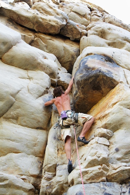 Llegar a la cima Un escalador escalando un acantilado