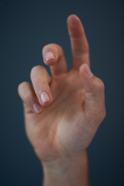 Foto llegar y echar una mano foto de estudio de la mano de un hombre irreconocible contra un fondo azul.