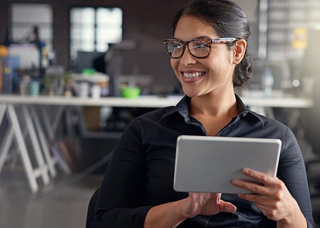 Llegar y tocar el futuro Captura de una mujer de negocios usando su tableta digital en una oficina