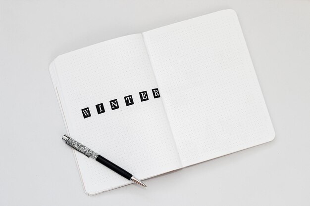 Llenando el diario escribiendo Invierno en un cuaderno con un punto