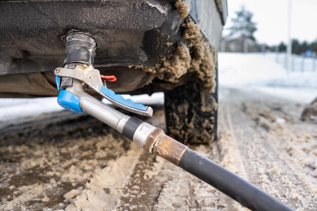 Llenar el automóvil desde la parte inferior del parachoques con gasolina en el invierno en la estación de servicio.