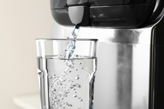 Llenar el vaso con agua del enfriador moderno