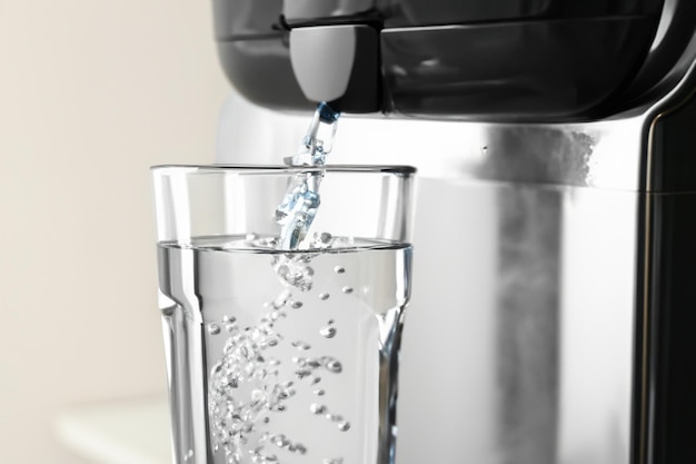 Foto llenar el vaso con agua del enfriador moderno