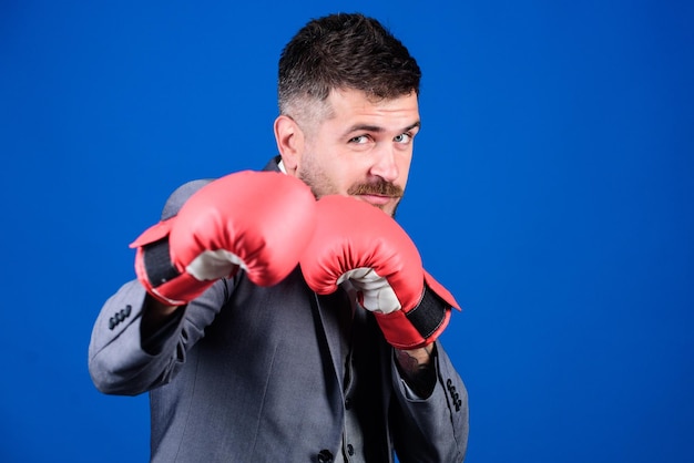 Foto lleno de energía hombre barbudo en guantes de boxeo golpeando éxito empresarial y deportivo boxeador de hombre poderoso listo para la batalla corporativa hombre de negocios en traje formal y corbata de moño nocaut y lucha de energía