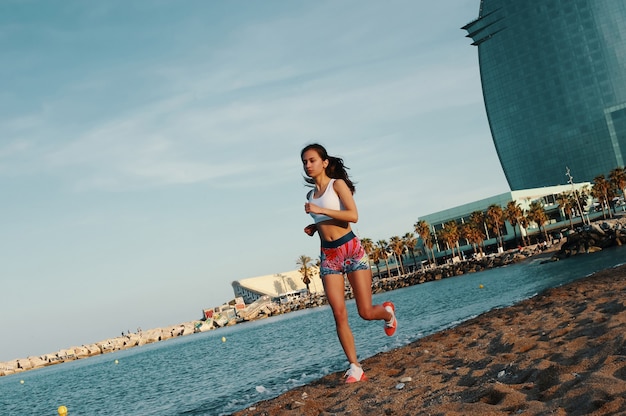 Lleno de energía. Longitud total de mujer joven atractiva en ropa deportiva para correr mientras hace ejercicio al aire libre