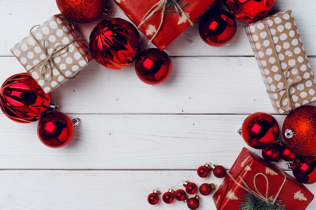 Lleno de pequeños regalos de Navidad y adornos rojos en la vista superior de la placa de madera blanca