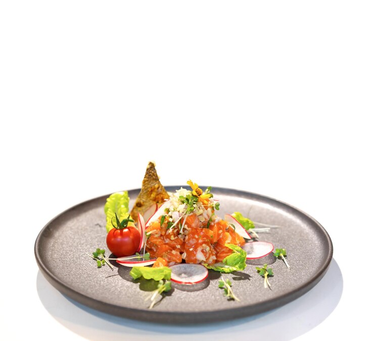 lleno de salada de salmón crudo picante estilo de comida tailandesa decorado con piel de pescado frito crujiente flor amarilla y micro hierba en fondo blanco aislado Camino de recorte