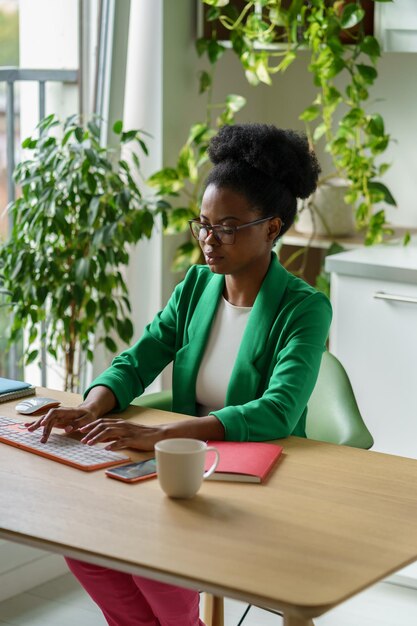 Llevada mujer de negocios afroamericana escribiendo en el teclado para preparar o correo electrónico importante