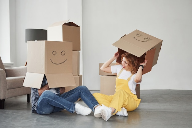 Llevando cajas en las cabezas. Pareja feliz juntos en su nueva casa. Concepción de mudanza