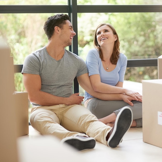 Llevando nuestra relación a un nivel completamente nuevo Foto de una joven pareja feliz relajándose en su nuevo hogar mientras se mudan