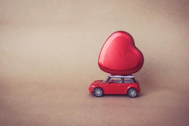 llevar amor día de San Valentín: coche rojo miniatura que lleva un corazón rojo