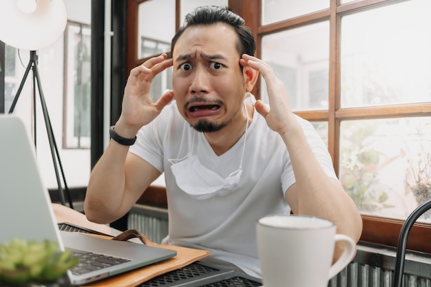 Llorando y sorprendido rostro gracioso del hombre decepcionar su trabajo en su computadora portátil