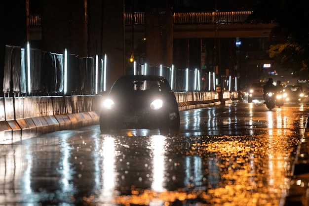 Llueve sobre la ciudad en calles con coches y motos.