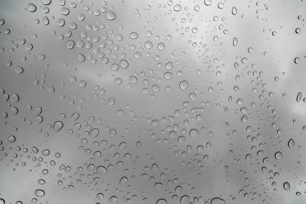 La lluvia cae sobre la superficie de los vidrios de la ventana con fondo nublado.