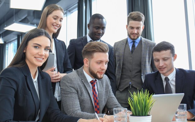 Lluvia de ideas Grupo de gente de negocios mirando la computadora portátil juntos Una mujer de negocios mirando a la cámara