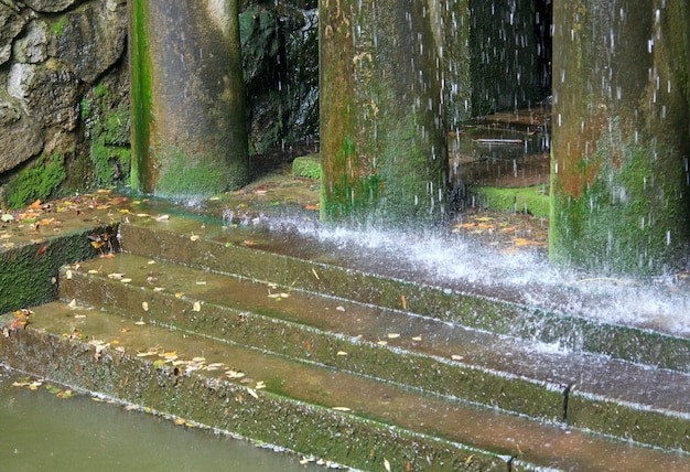 Lluvia y porche con pilares y escalones (composición de cascada en el parque de la ciudad vieja)