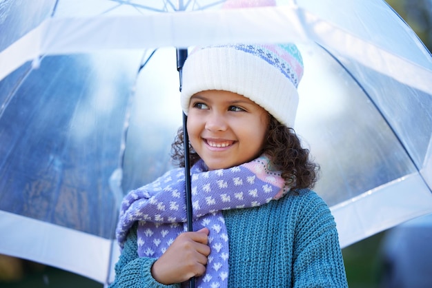 La lluvia siempre ha sido mi foto favorita de una niña adorable parada sola afuera y sosteniendo un paraguas