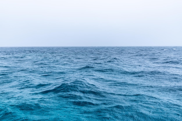 Lluvia sobre el mar tormentoso, el agua azul del océano y las gotas de lluvia. Vista al mar sin fin