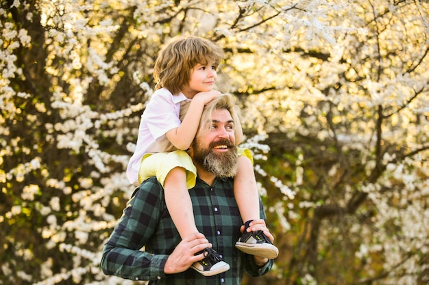 Lo hace volar. padre e hijo cerca de la flor del árbol de sakura. feliz Día del Padre. Celebremos juntos el día de los niños. amor y valores familiares. relajarse al aire libre juntos. somos familia. niño pequeño abraza a su papá.