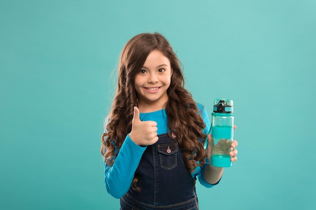 Lo mejor para su salud, una niña pequeña, sostenga una botella de desintoxicación y la gente, una bebida saludable para un niño adolescente. Beba agua para el cuidado de la salud y el equilibrio corporal. Un niño sediento beba agua, beba agua para prevenir la deshidratación.