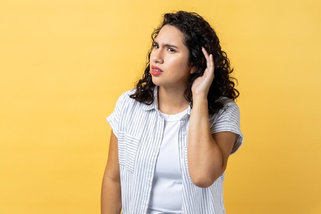 Lo que no puedo oírte Mujer de pie con la mano en la oreja y quiere oír algo