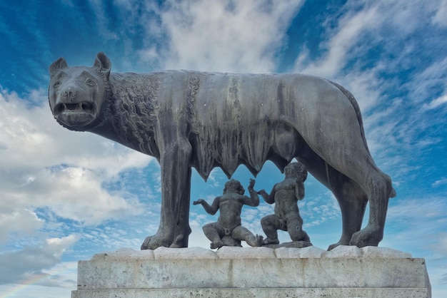 Foto loba símbolo do império romano amamentando o recém-nascido romulus e remus estátua em fundo de céu azul