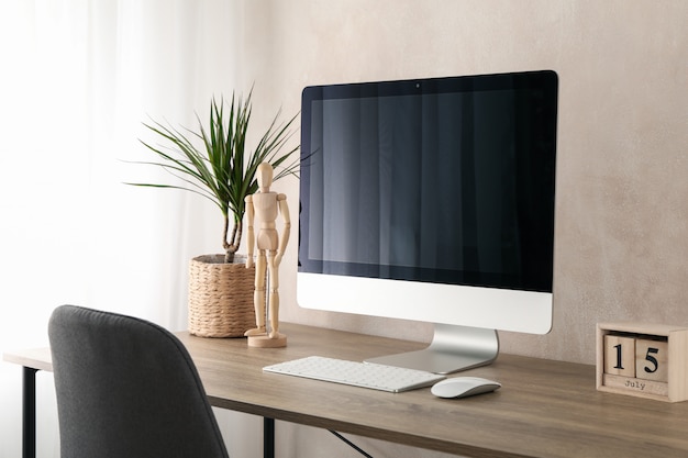 Local de trabalho com computador e planta na mesa de madeira. Marrom claro