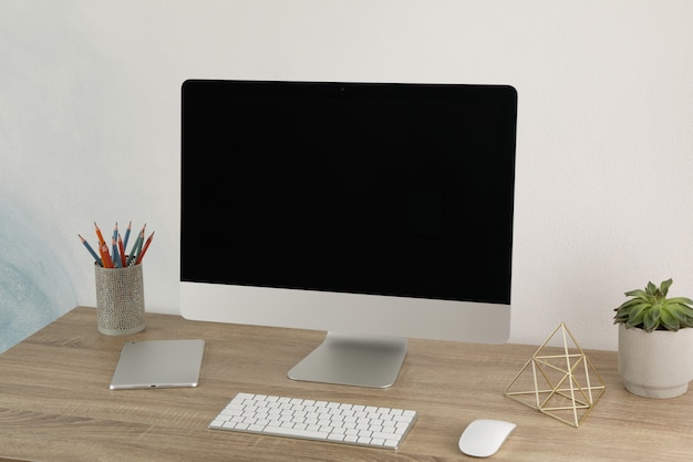 Local de trabalho com computador, planta e tablet na mesa de madeira. Tela preta vazia